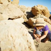 girl playing near big rocks at the beach