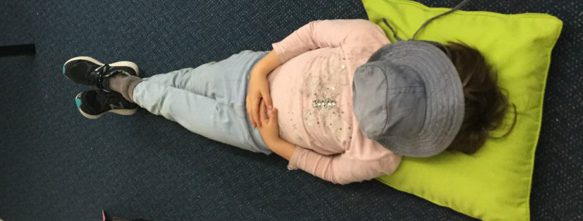 A child lying on the floor doing mindfulness