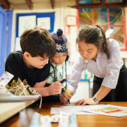 Chinese Student Teacher showing two boys something written in a book