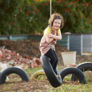 Girl riding a tire hanging from tree