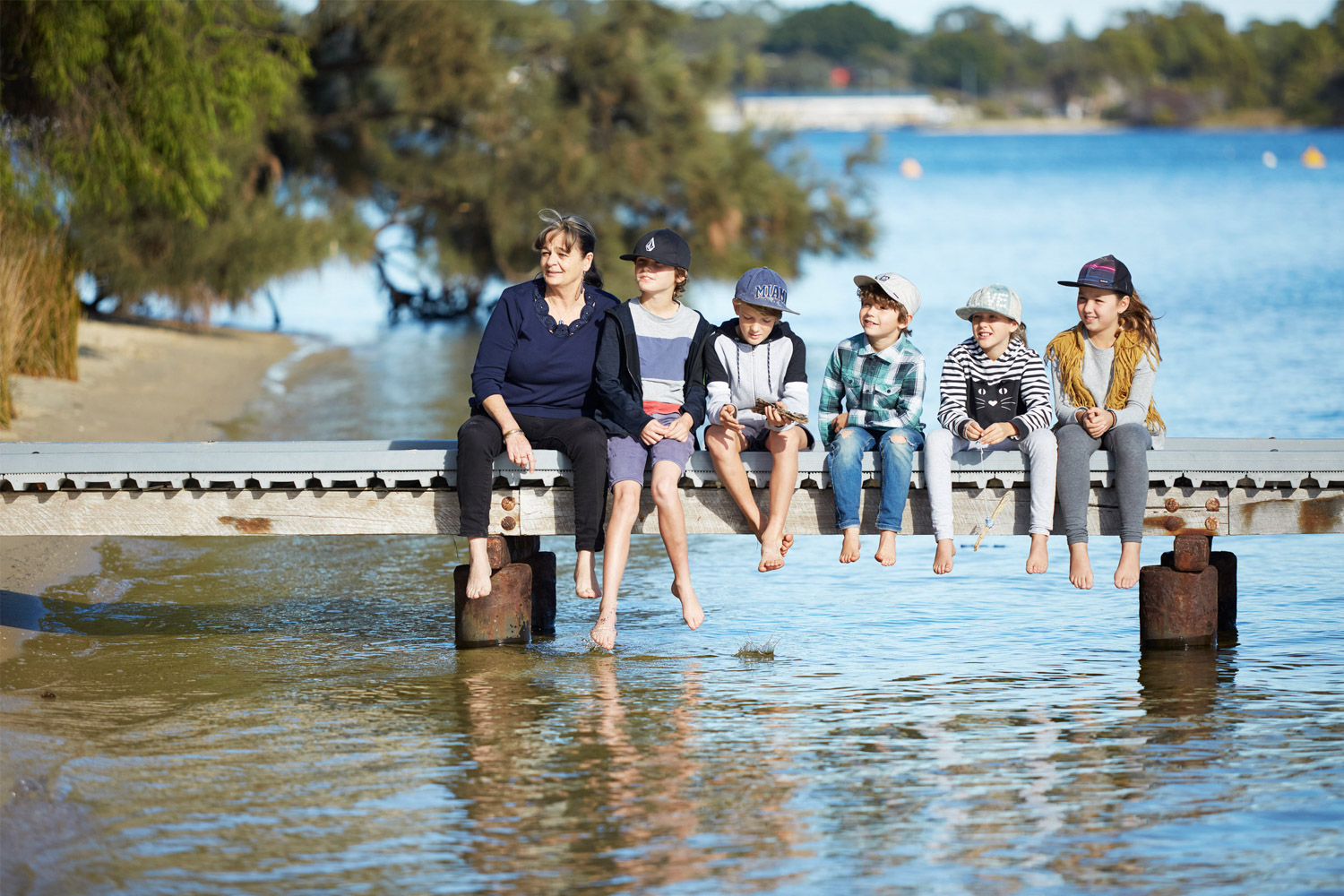 teacher and children sitting on jetty at river