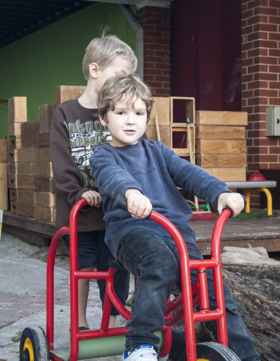 students riding tricycle in school yard